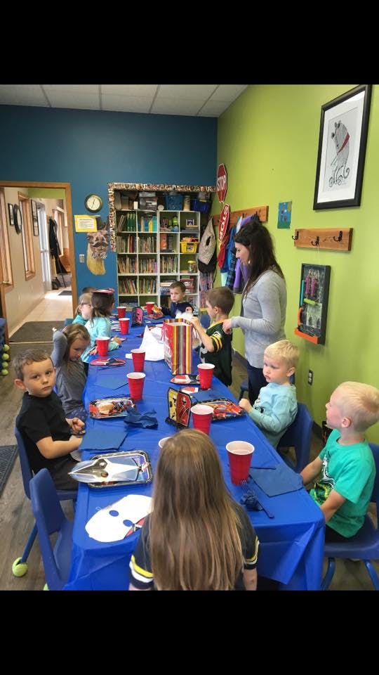 Adult and children seated at a long table in a classroom