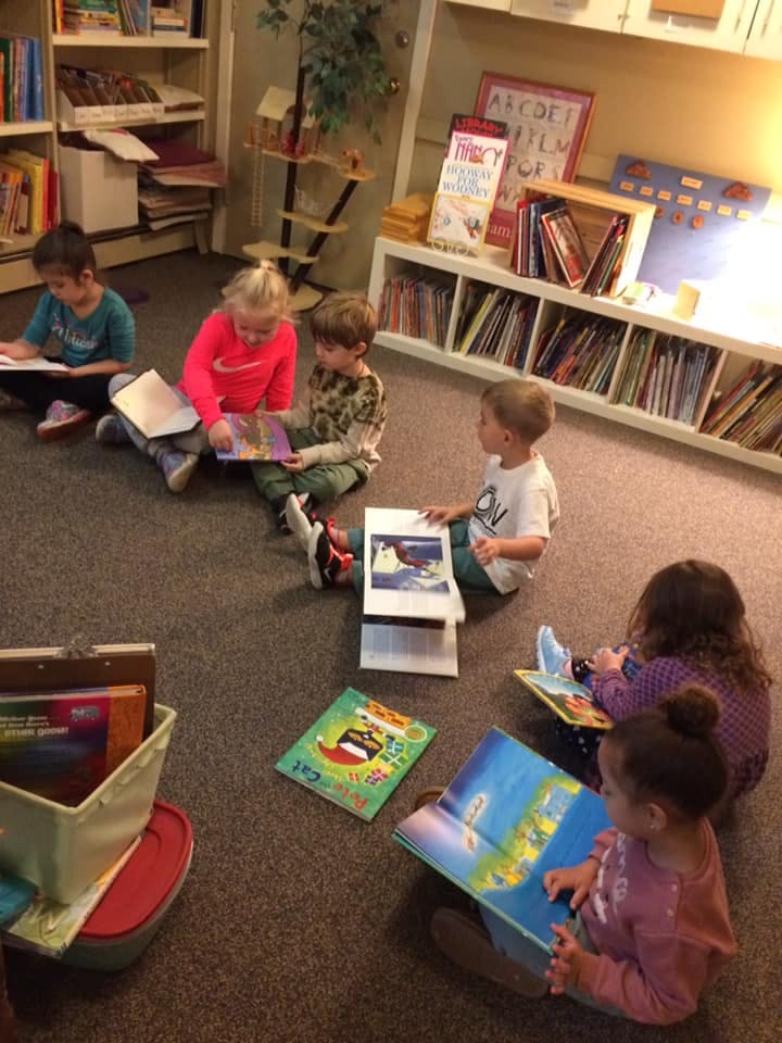 Children sitting on the floor reading books in a library