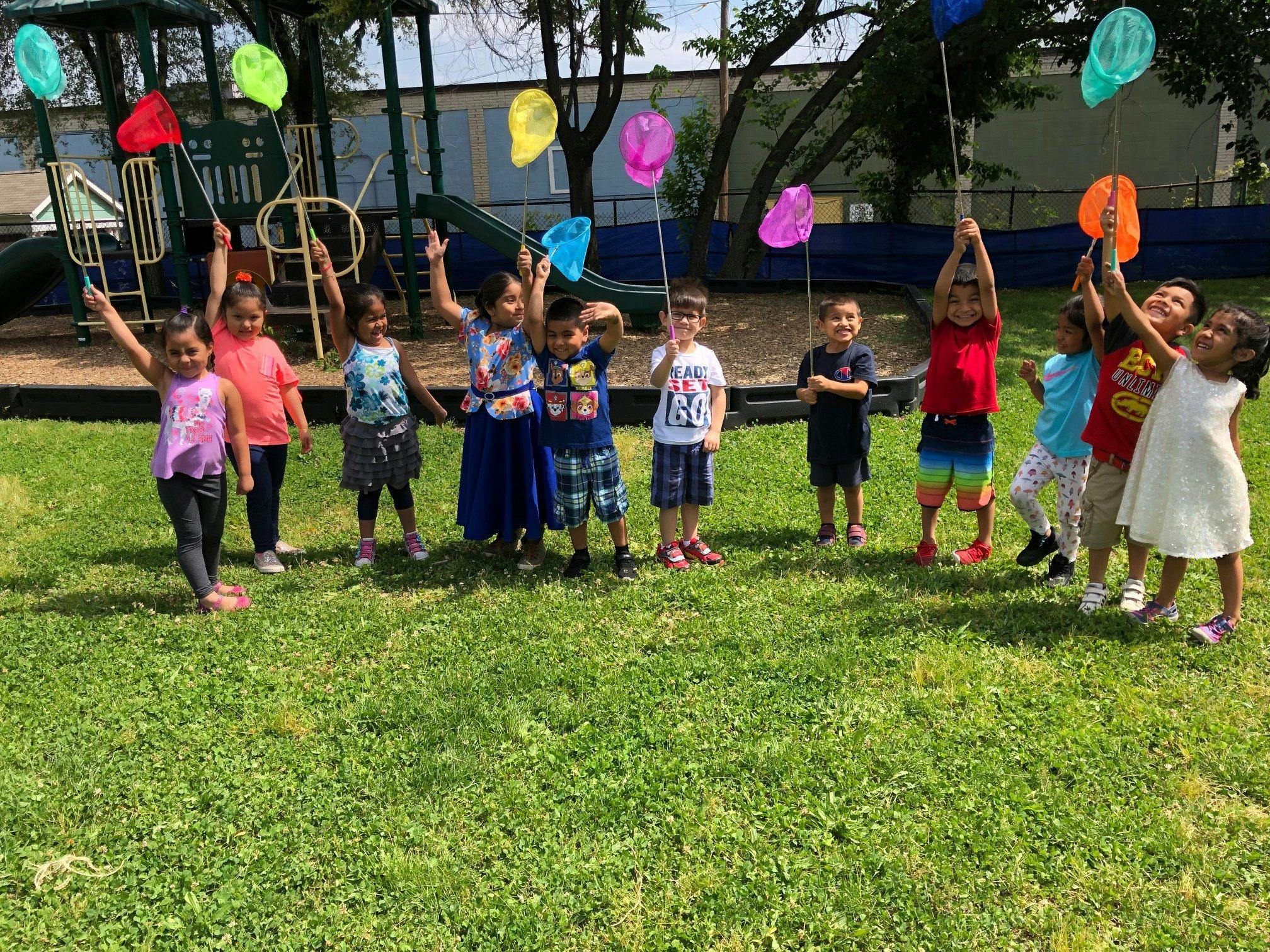 Children holding colorful butterfly nets in a grassy area