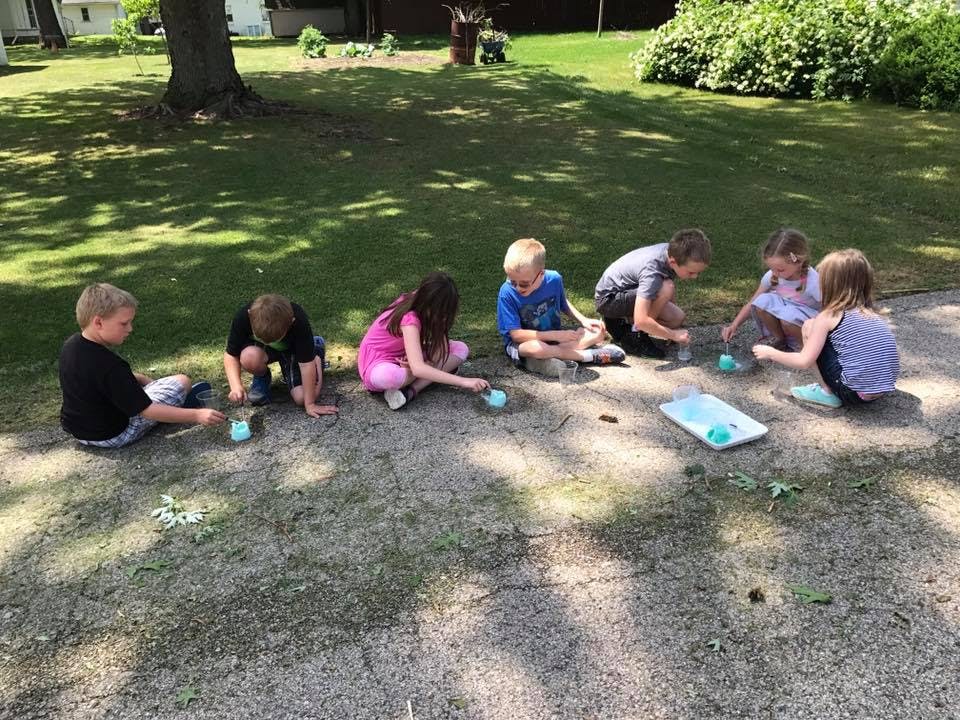 Group of children sitting on the ground playing with small objects