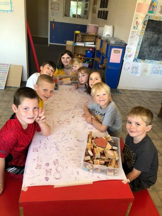 Group of children and adults sitting around a table with a box of blocks