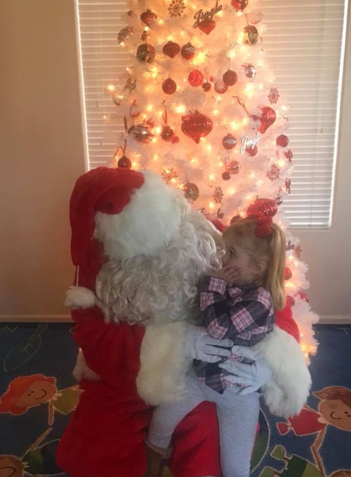 Person in red suit and white beard holding a child