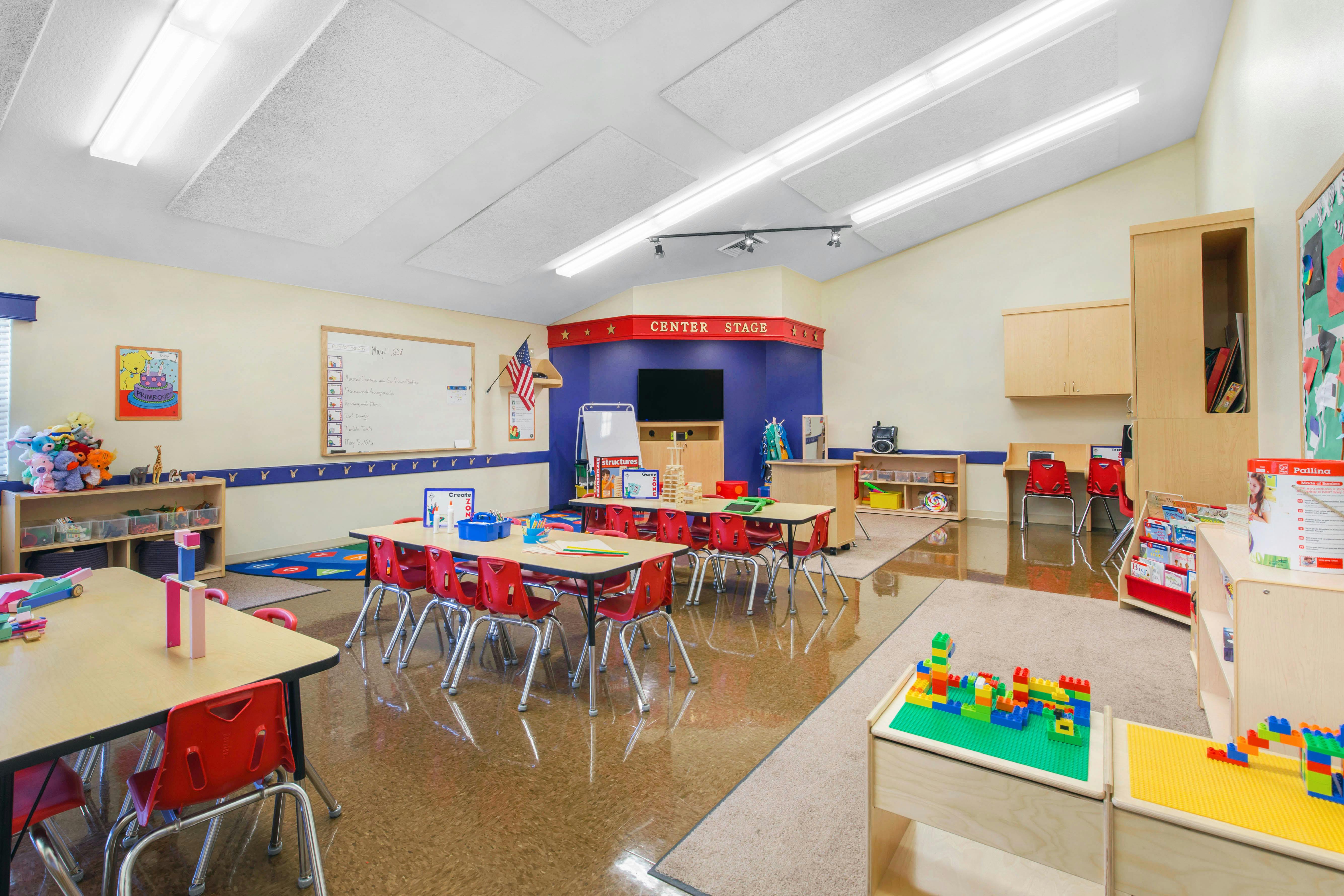 An empty early childhood classroom with small tables and chairs