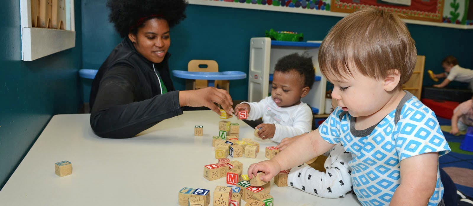 Person and two children playing with blocks atable of blocks