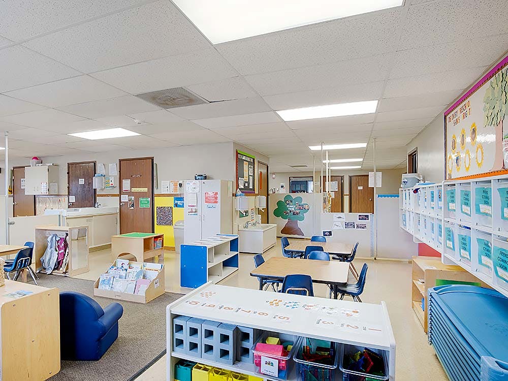 Empty colorful preschool classroom with small tables and chairs