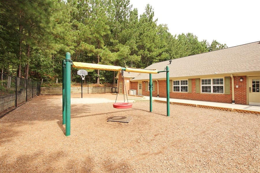 Playground with swing set and basketball hoop next to a building