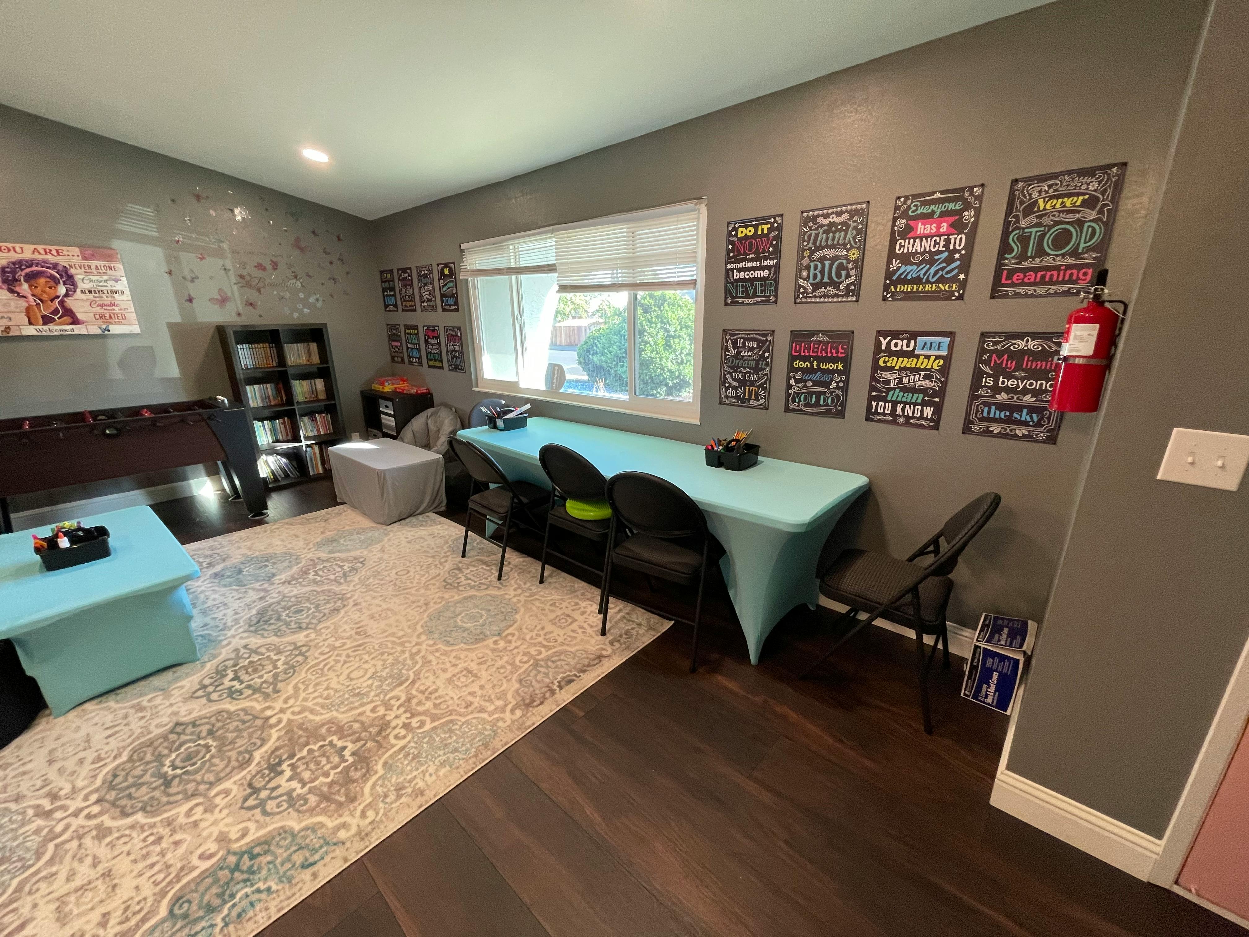 Room with tables covered in light blue cloths, chairs, and wall decor