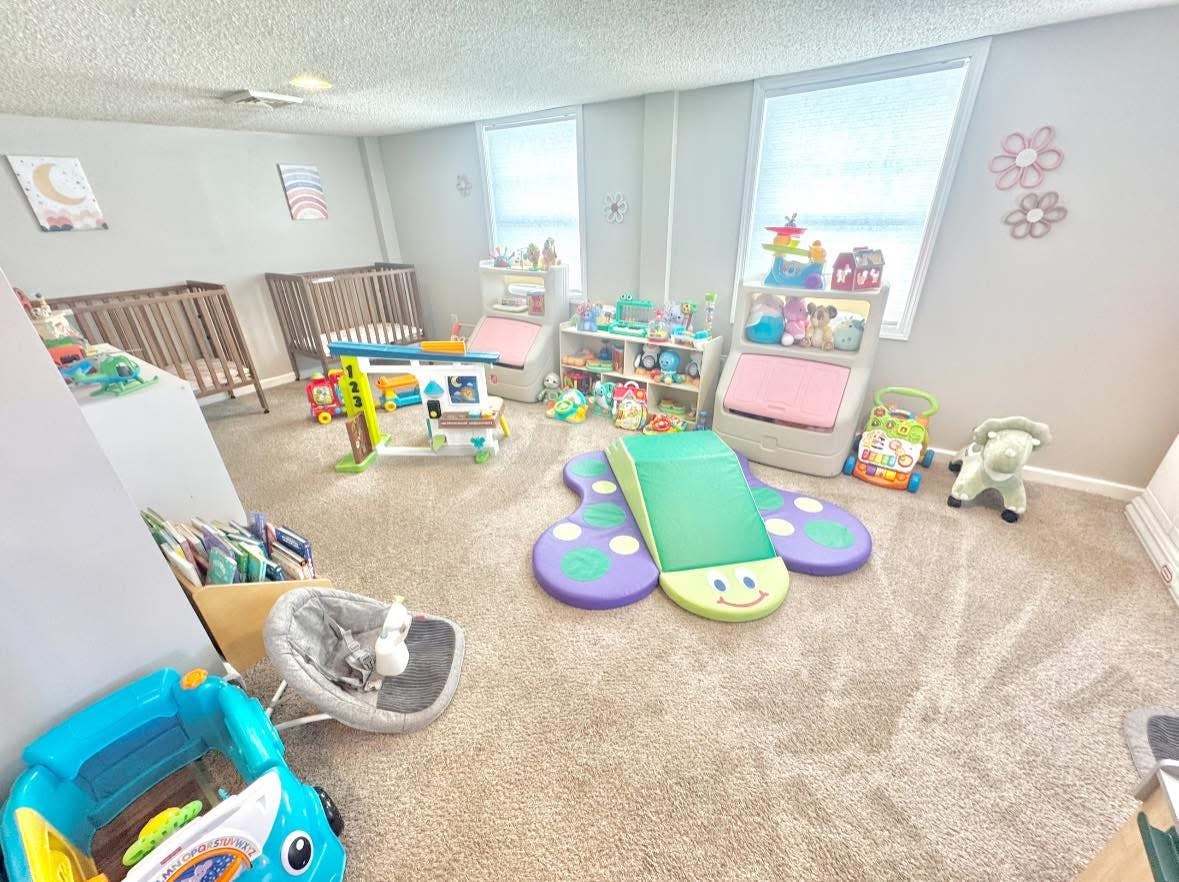 Baby room with two cribs, a butterfly play mat, and various infant toys
