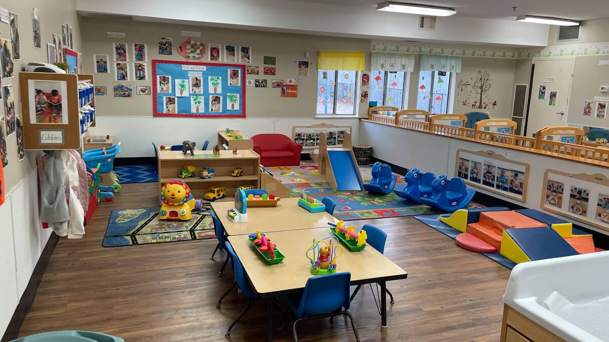 A colorful childcare classroom with toys, tables, and soft play equipment