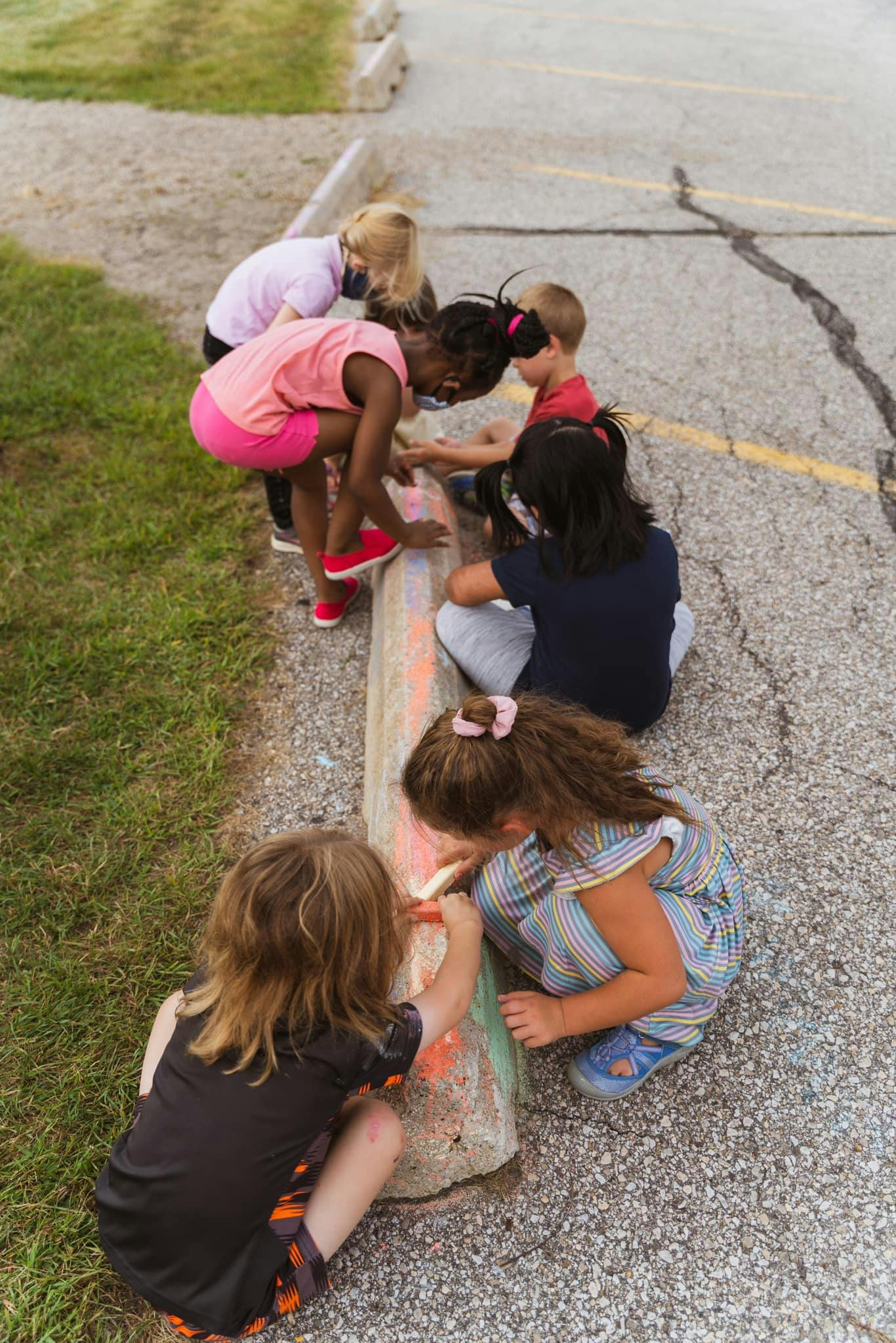 Children drawing with chalk on a curb
