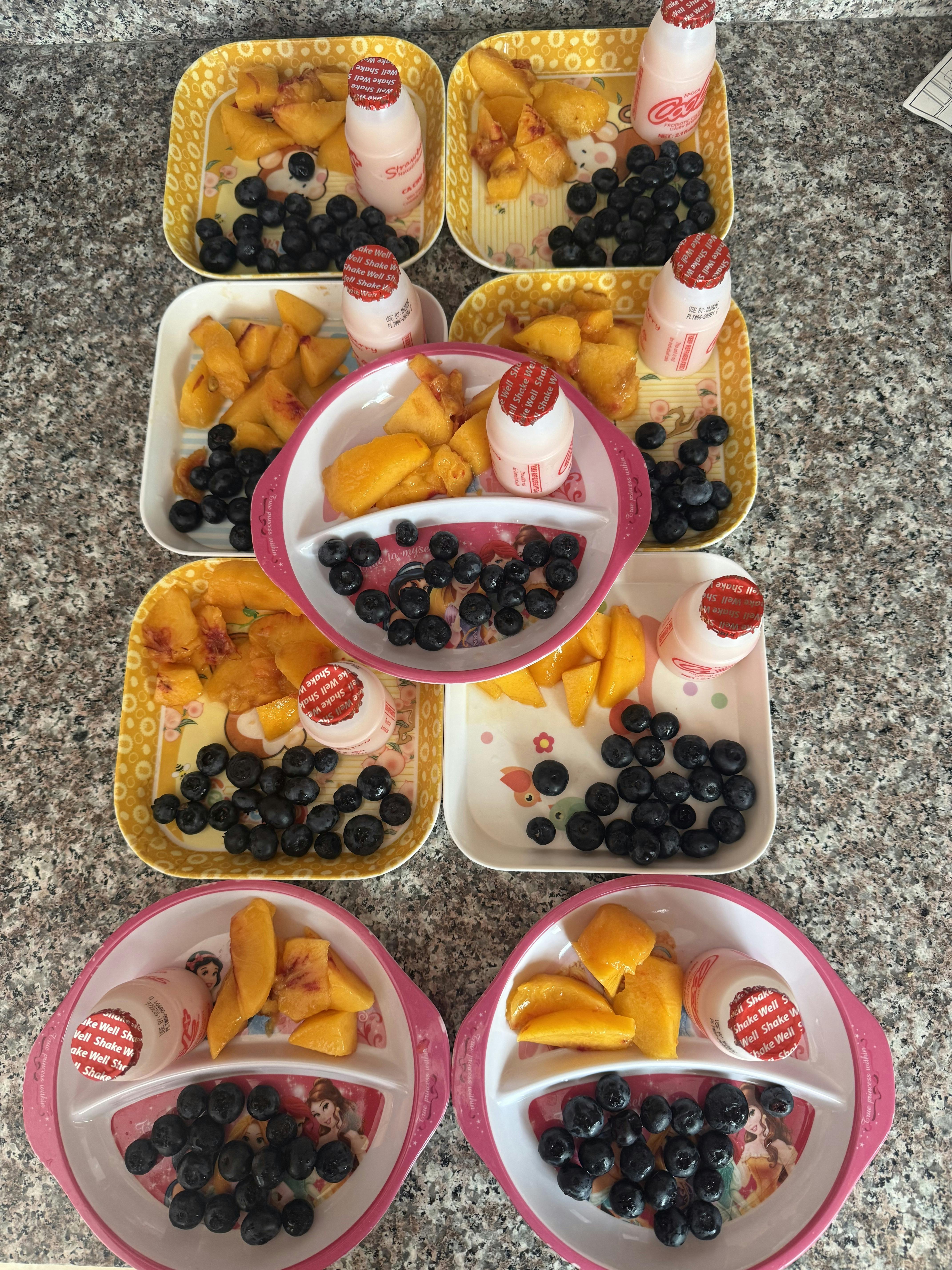 Plates served with sliced peaches, blueberries, and a yogurt drink
