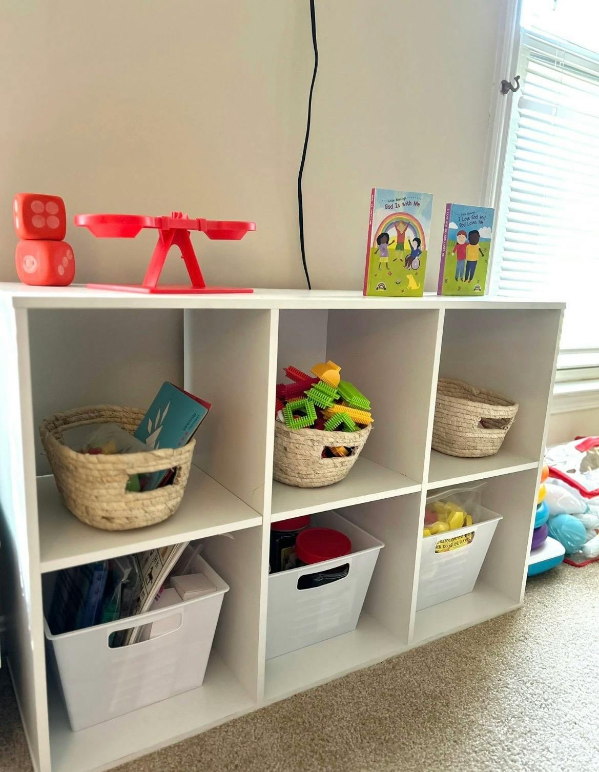 White storage shelf with baskets and books
