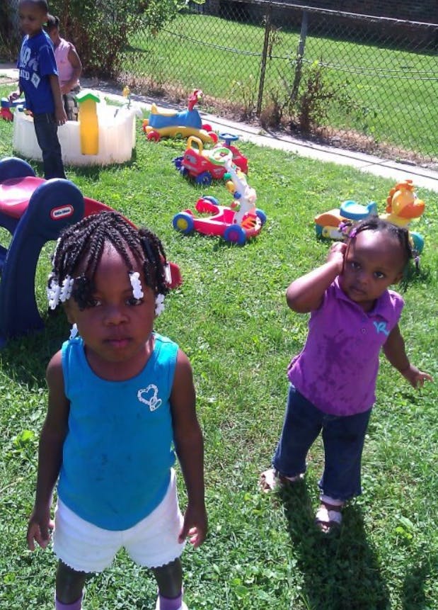 Two children standing in a grassy area with toys