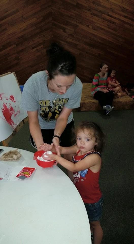 Person and child making something in a red bowl
