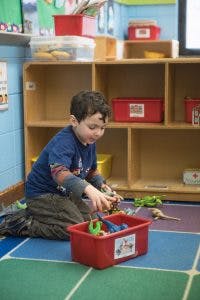 Child playing with toys in a red bin in a classroom