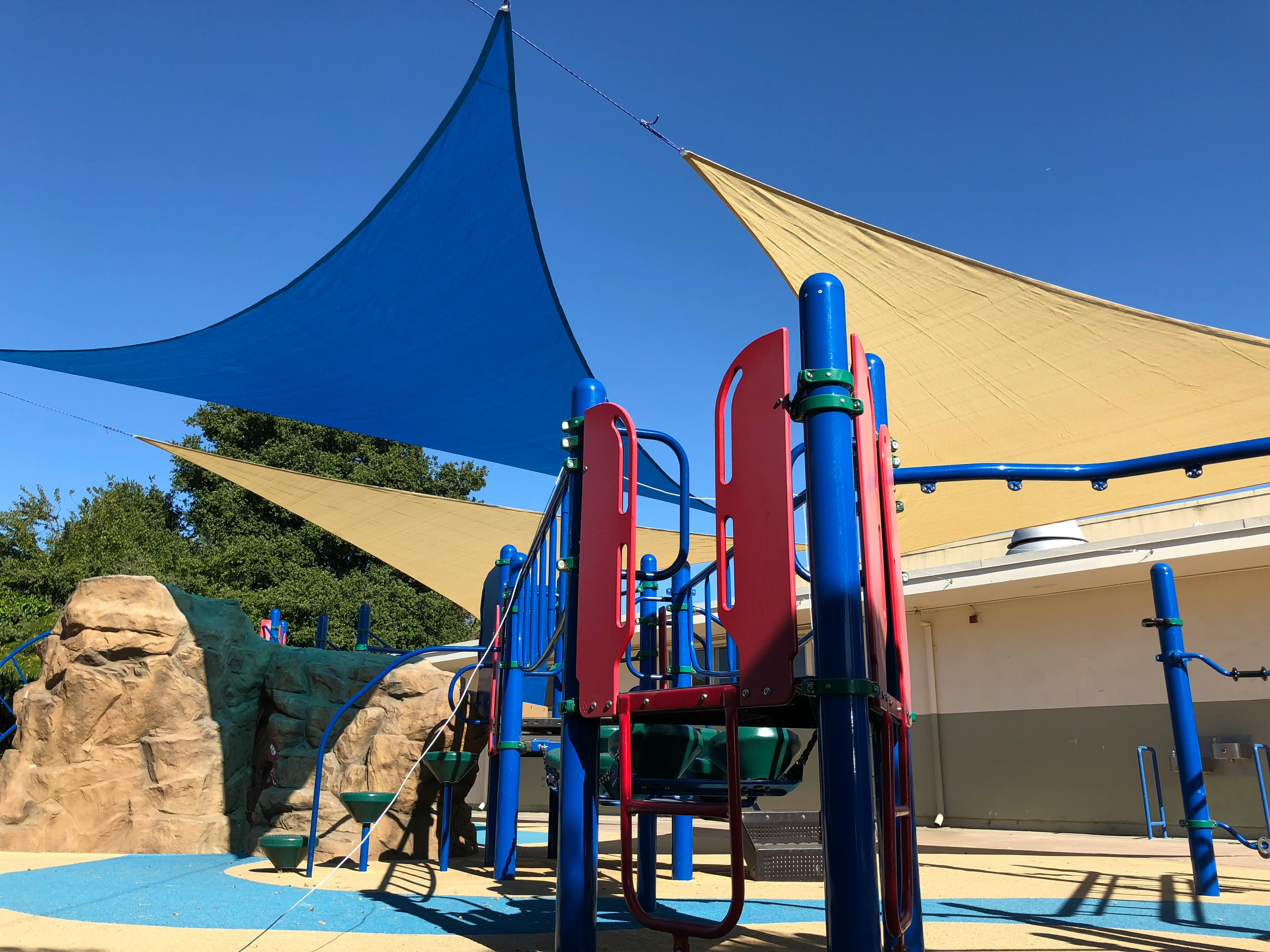 Playground with blue and red equipment under shade sails