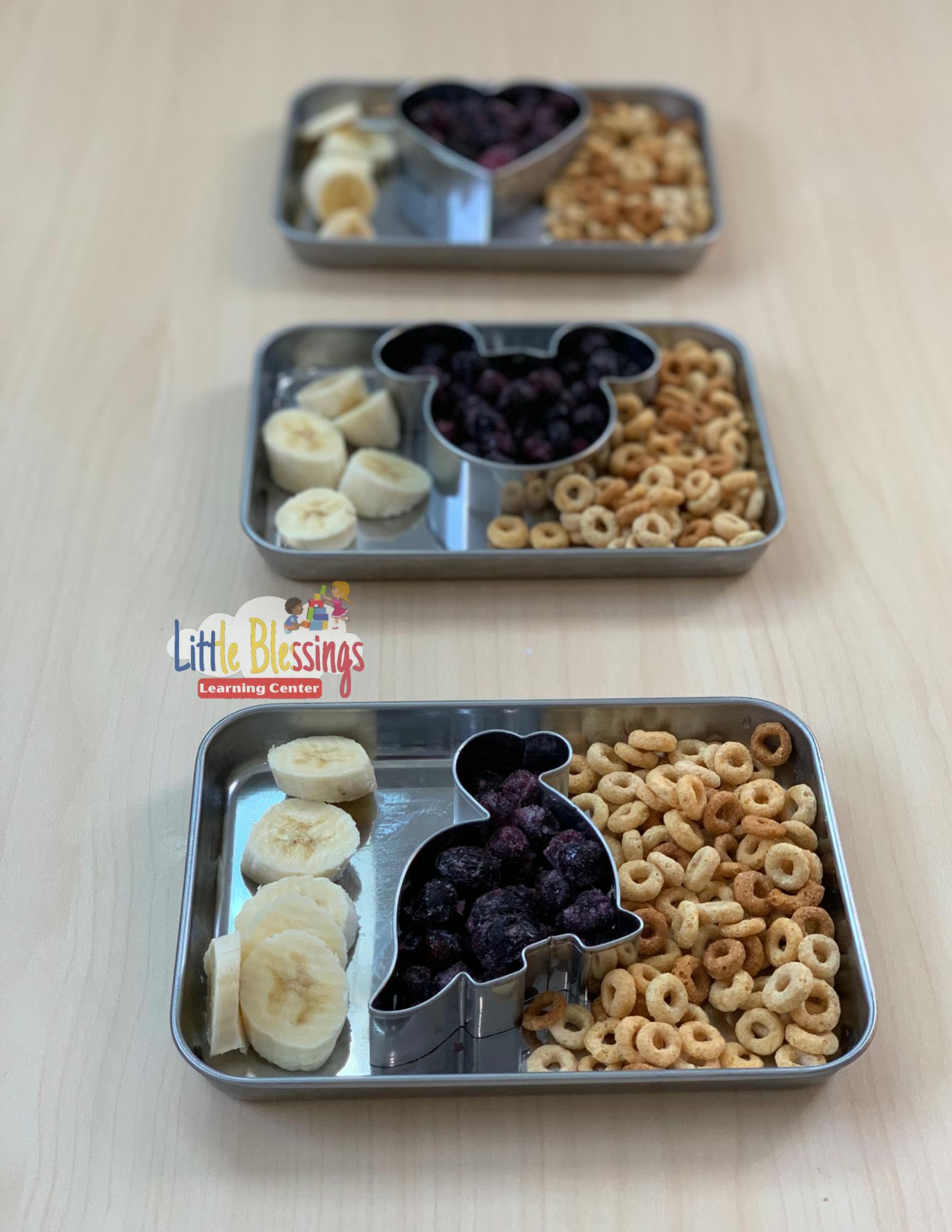 Three metal trays with bananas, blueberries, and cereal