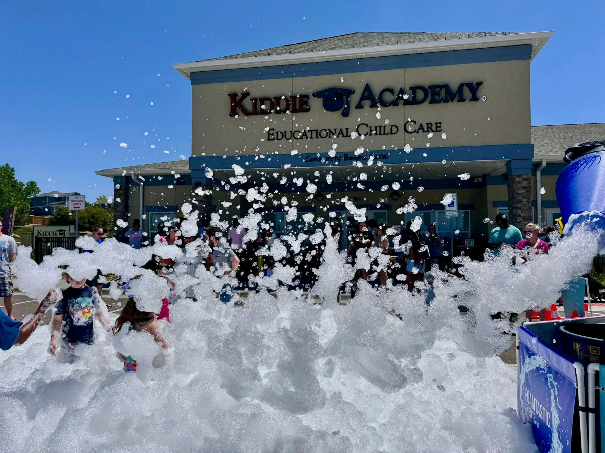 Children playing in a large pile of foam in front of a building