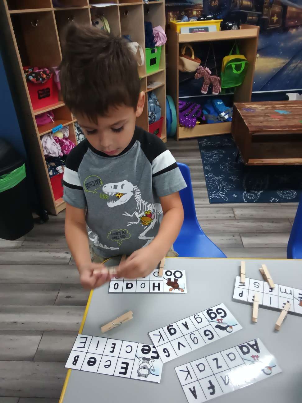 Child playing with letter cards and clothespins at a table