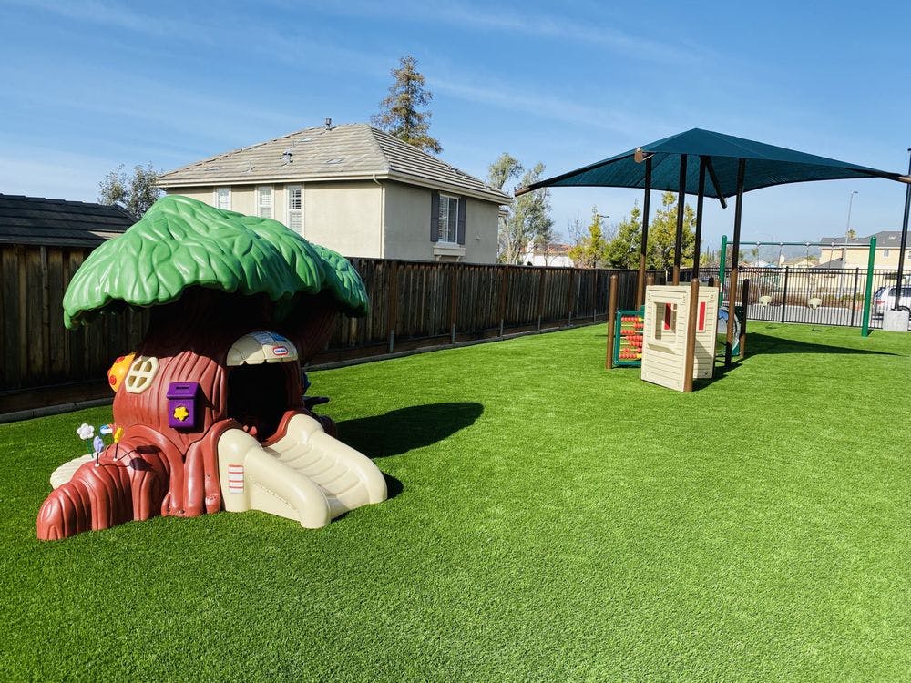 Playground with a treehouse-shaped play structure and a shaded play area