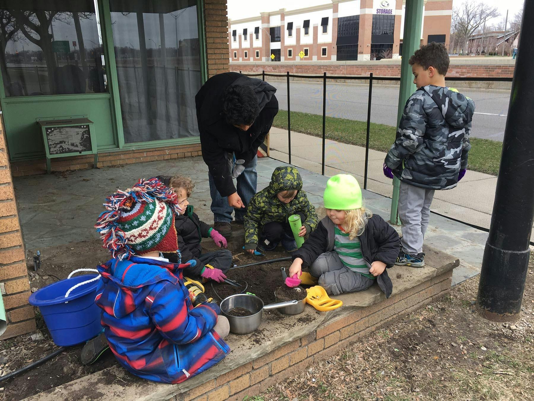 Adult and children playing in dirt with toys