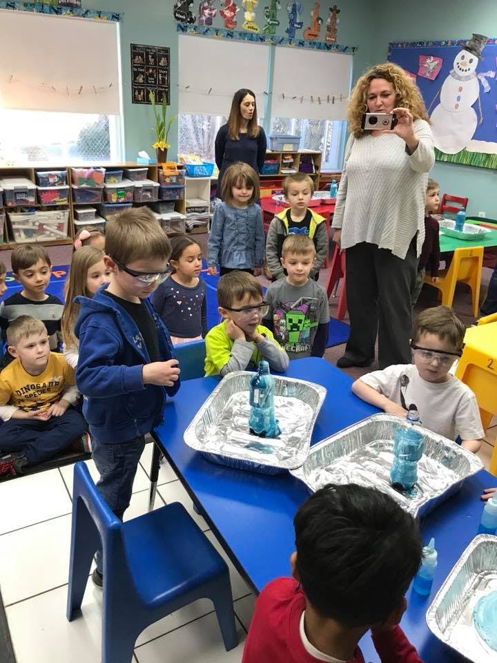 Adults and children in a classroom watching a science experiment