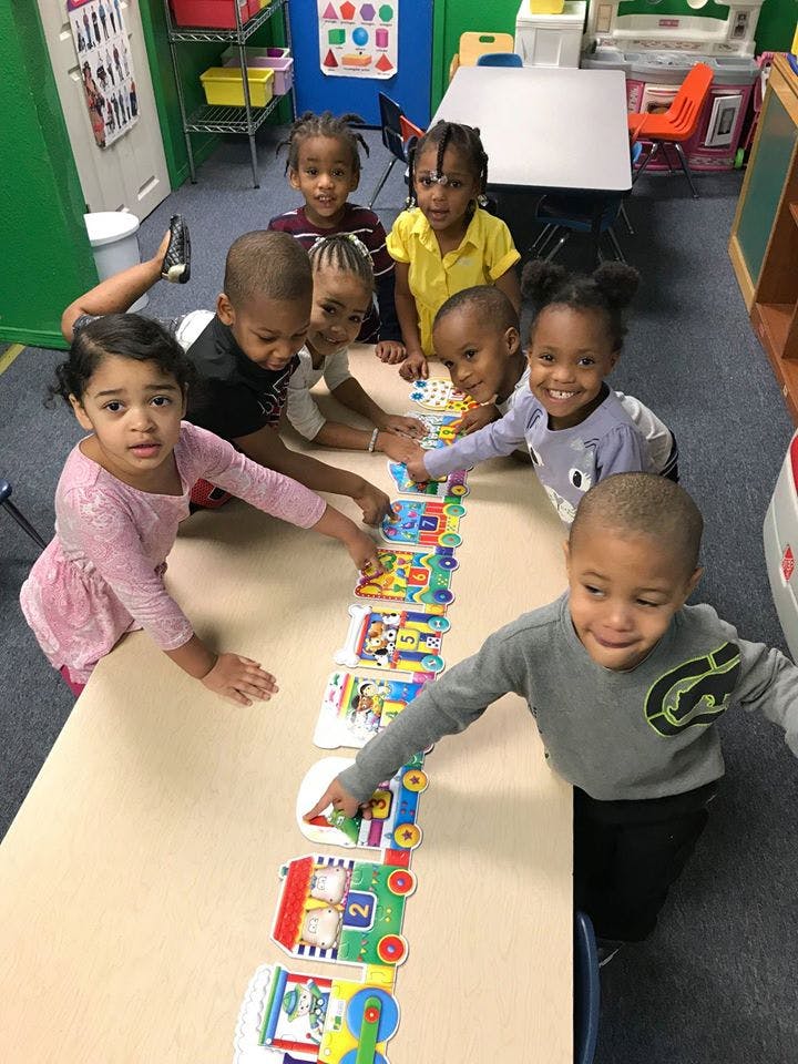Children playing with a long train puzzle on a table