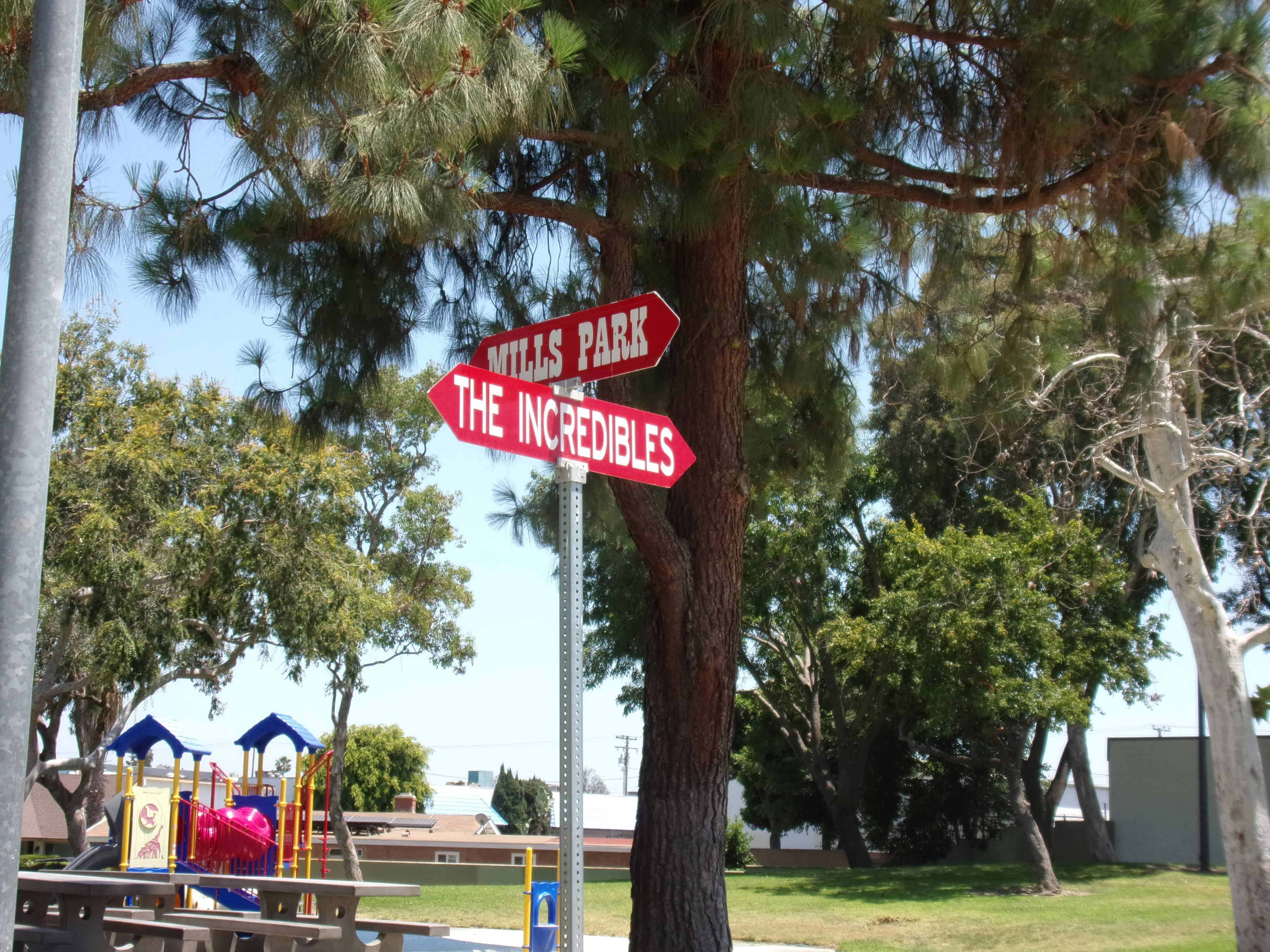 Red directional signs for "Mills Park" and "The Incredibles" on a pole