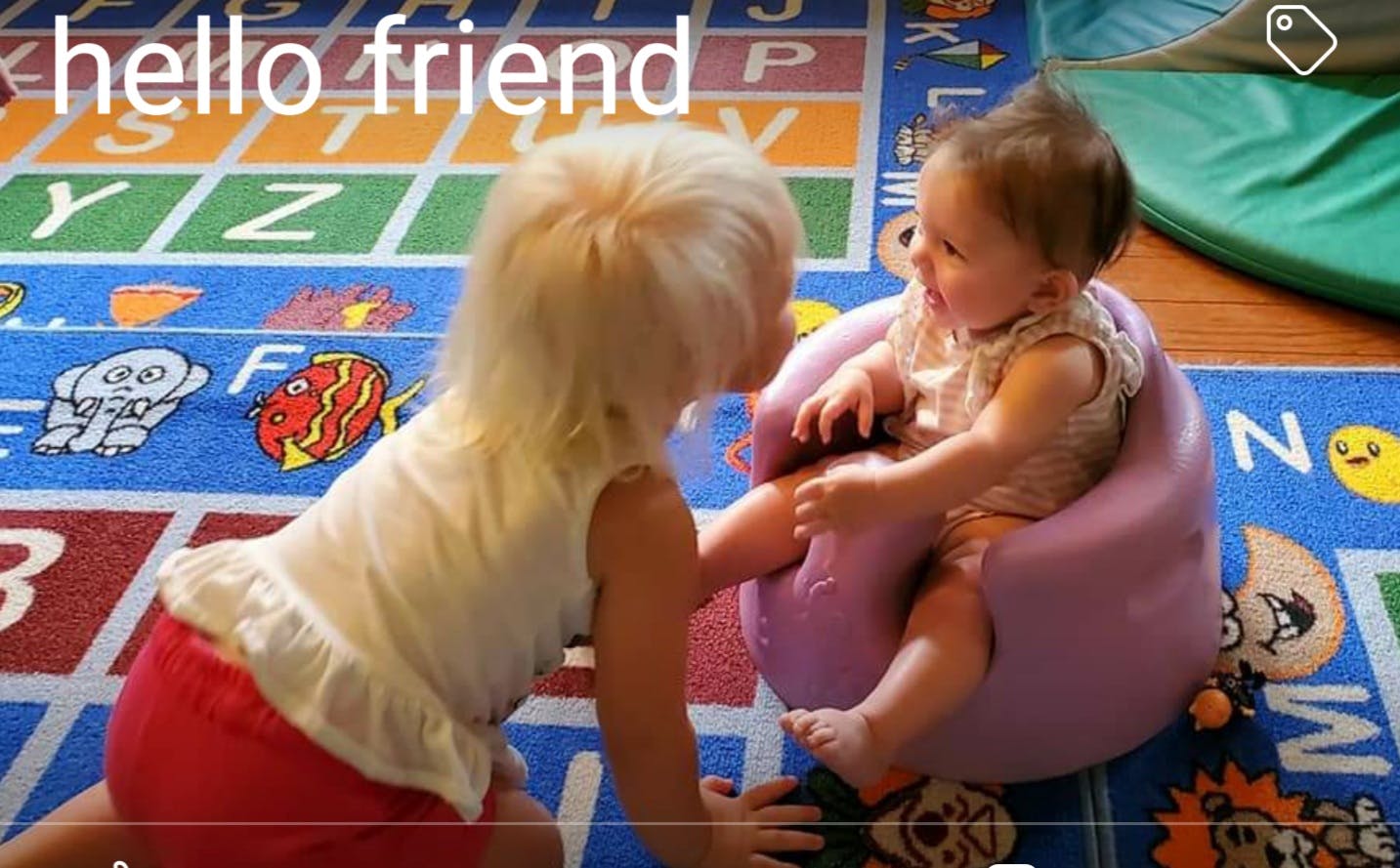 Child on knees looking at baby in a purple seat