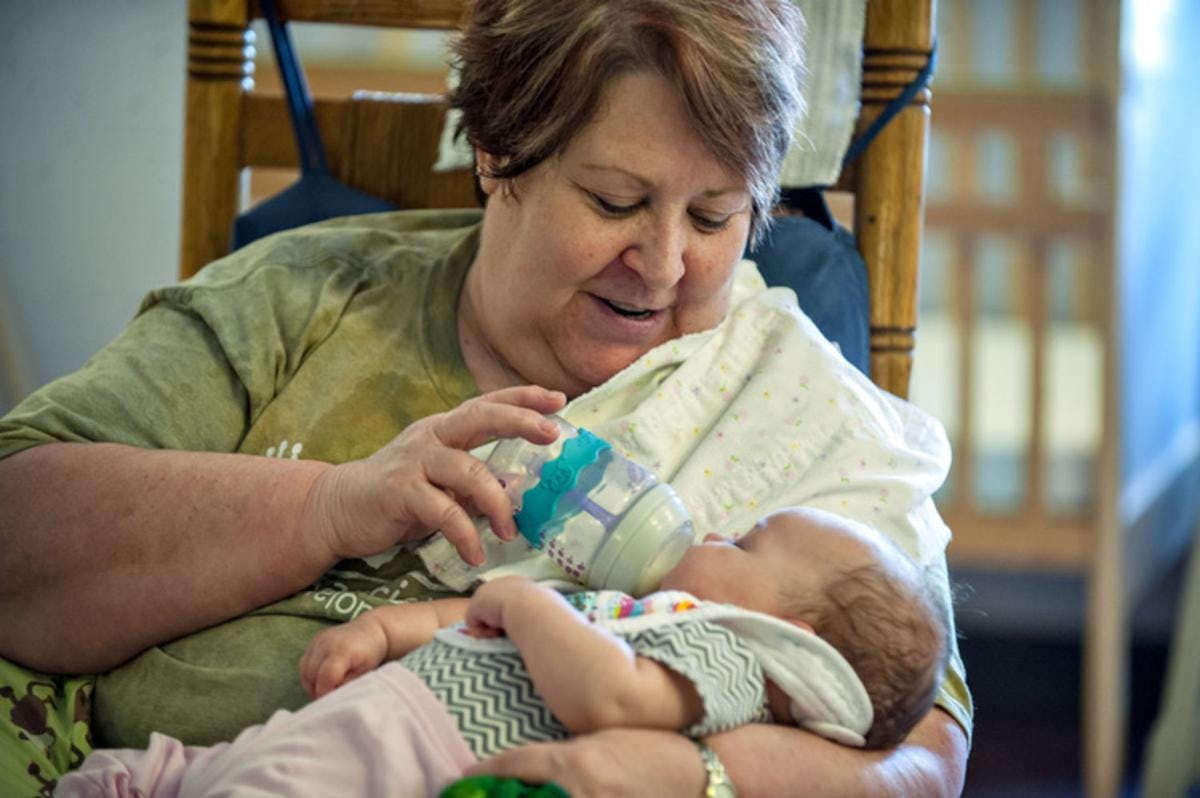 Person bottle-feeding a child