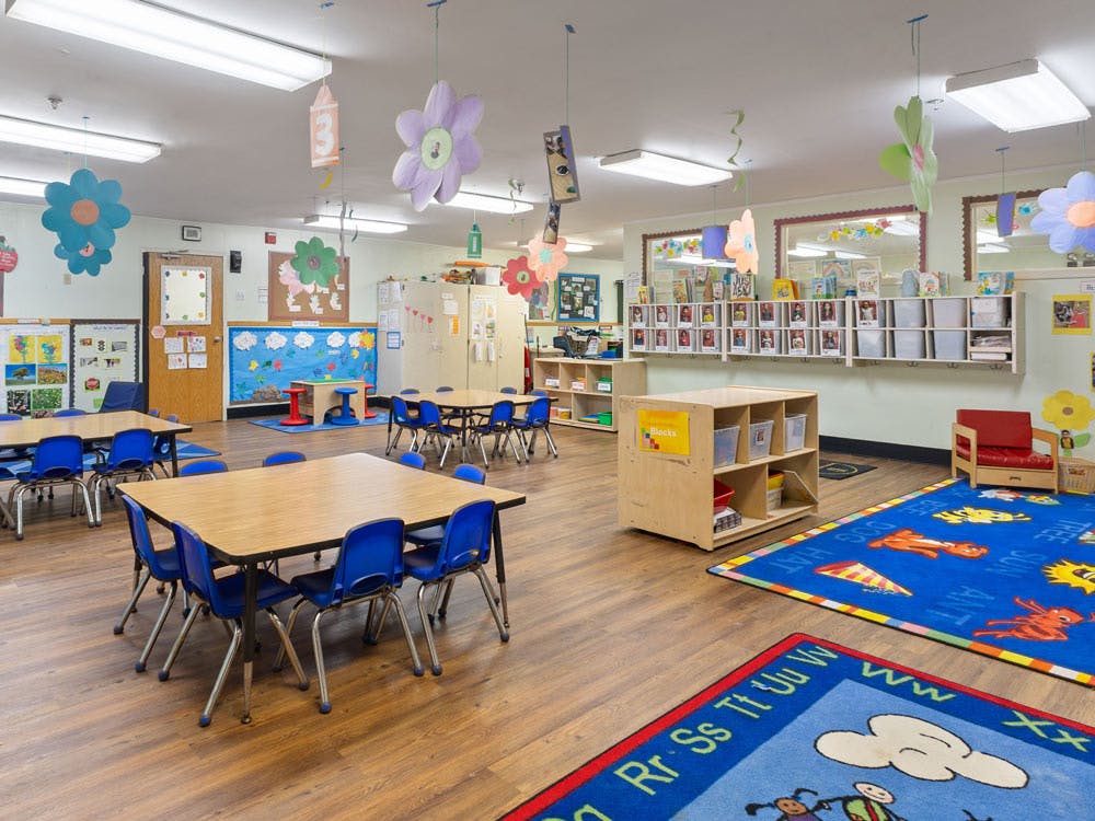 An empty classroom with tables, chairs, and colorful decorations