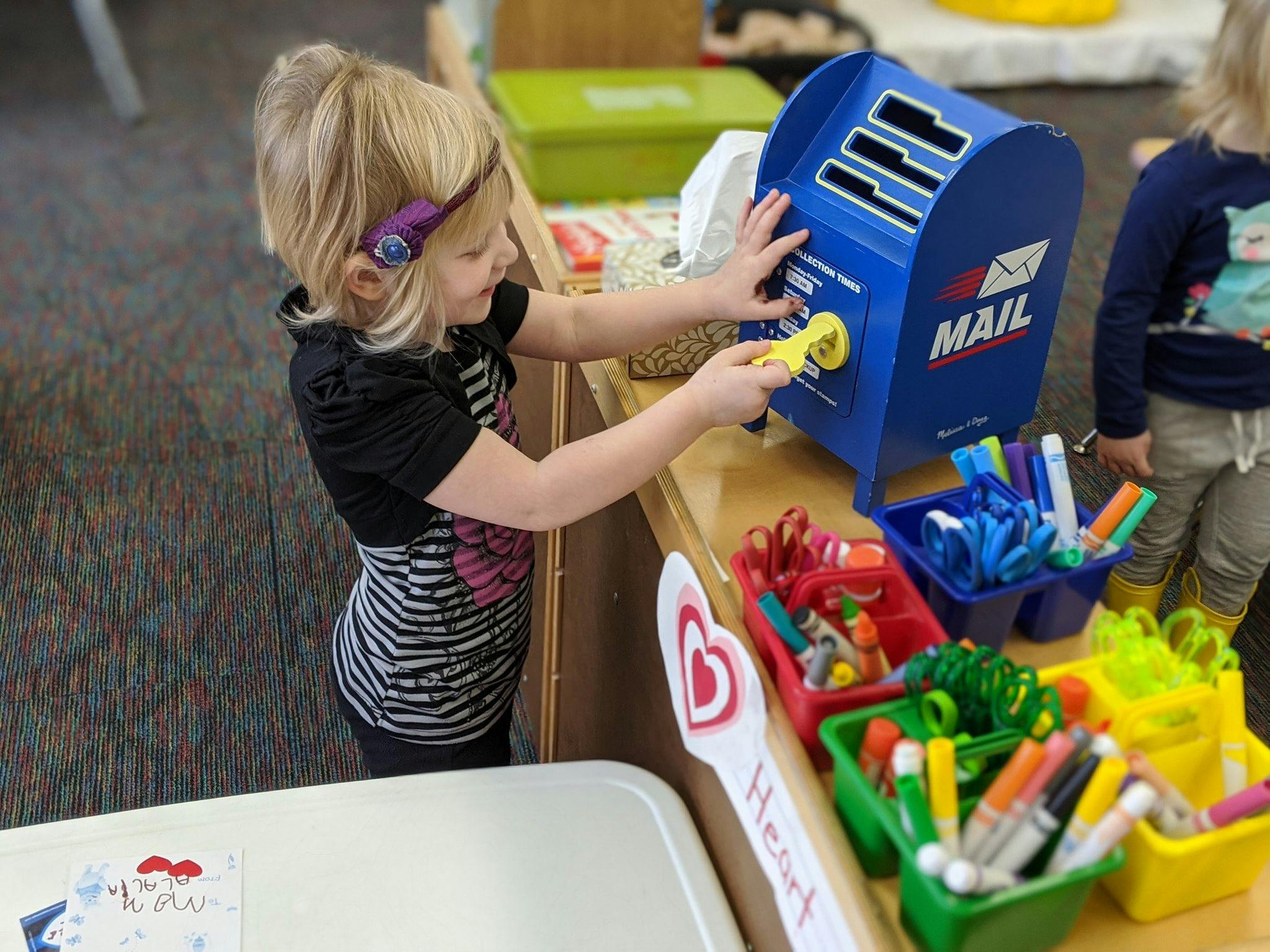 Child playing with a toy mailbox