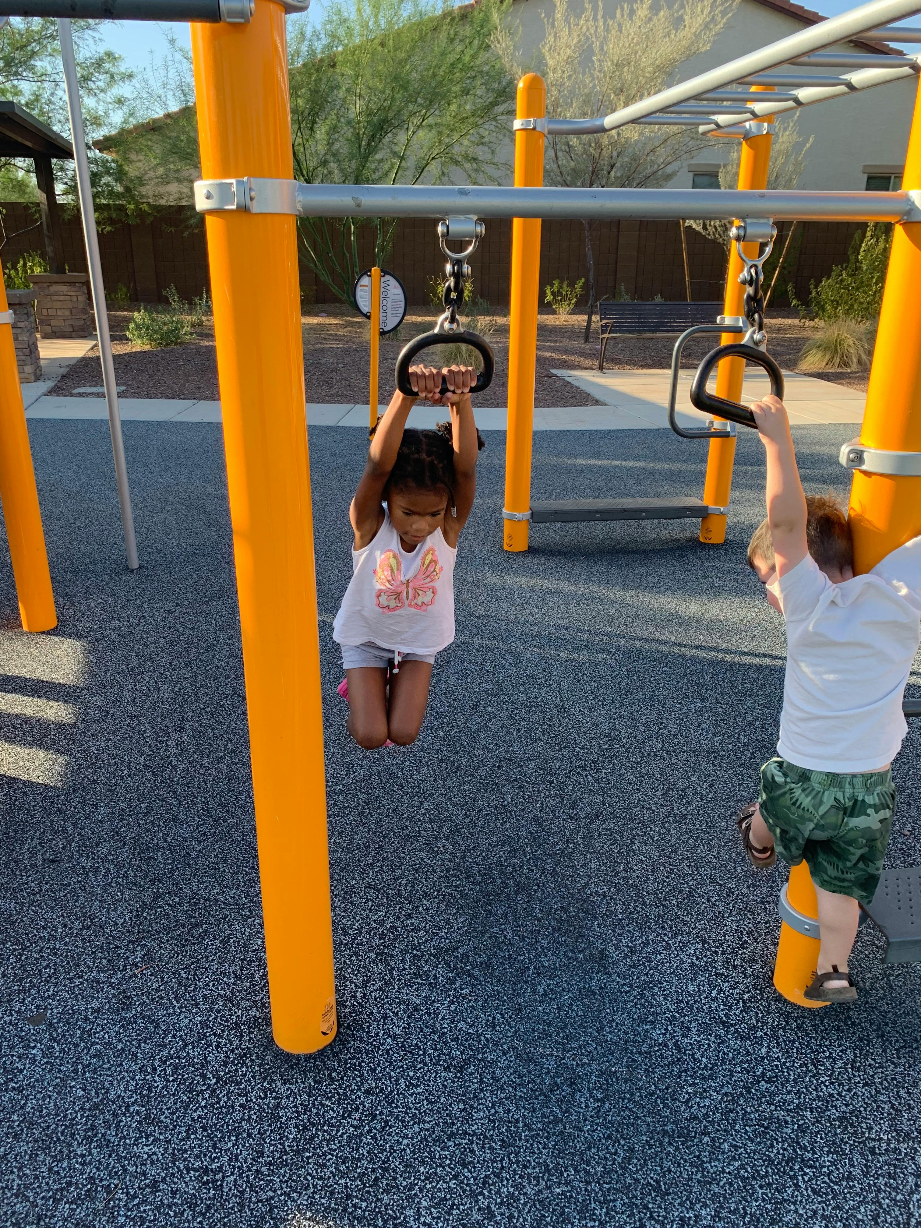Two children playing on monkey bars at a playground