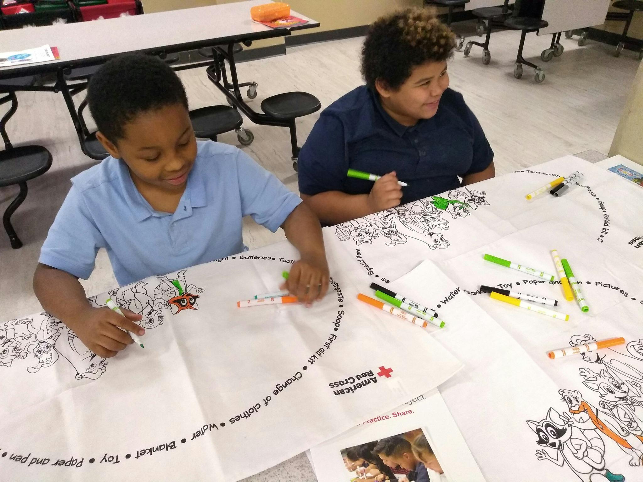 Two children coloring on large sheets of paper with markers