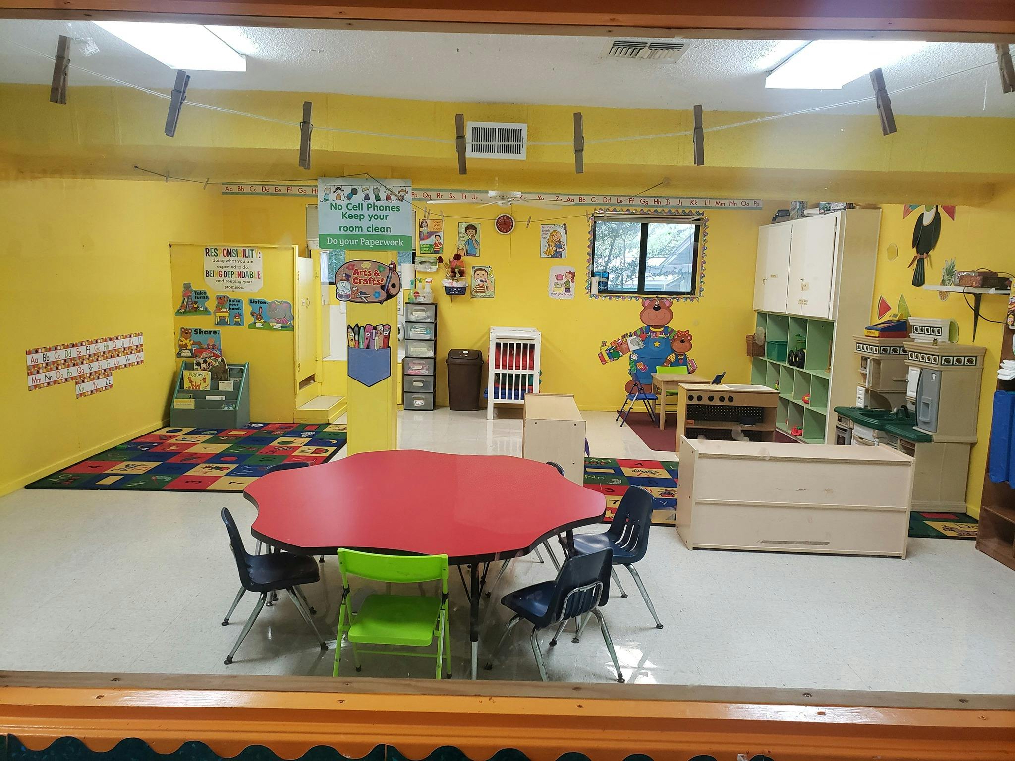 Empty classroom with yellow walls, red table, and colorful rug