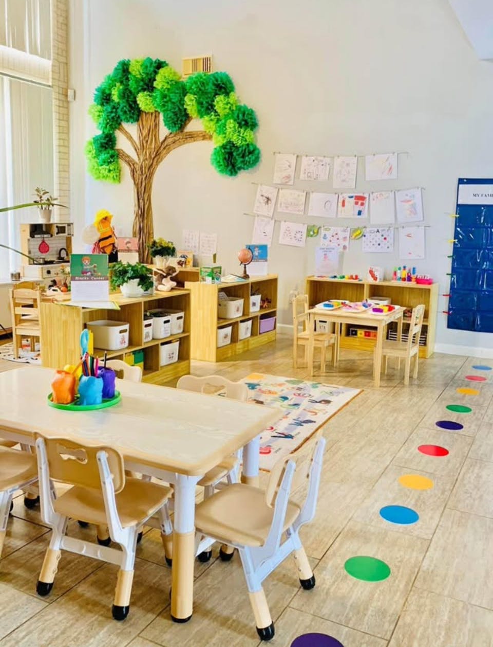Classroom with small tables and chairs, shelves, and a tree decoration