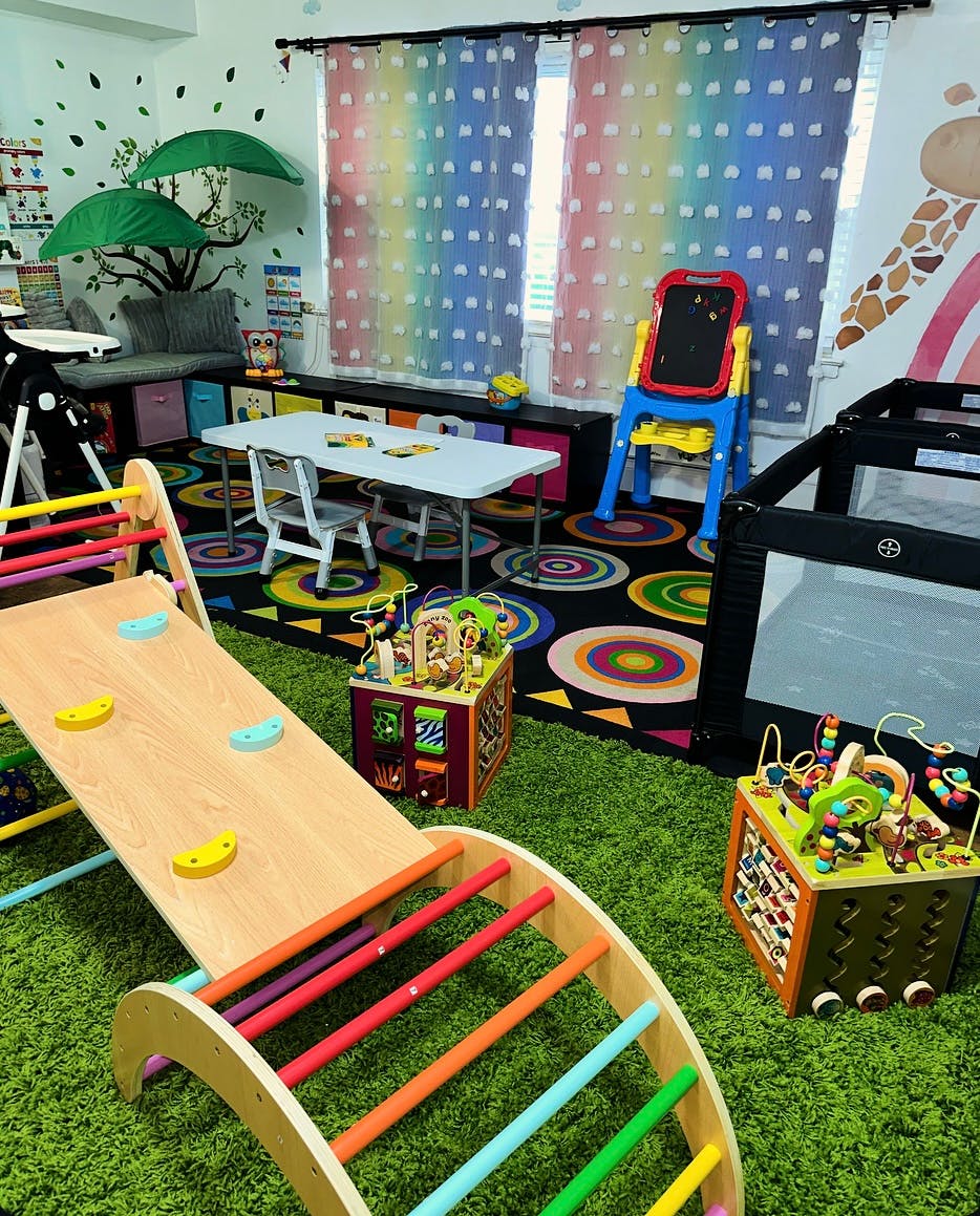 Indoor play area with a climbing structure, table and chairs, and playpen