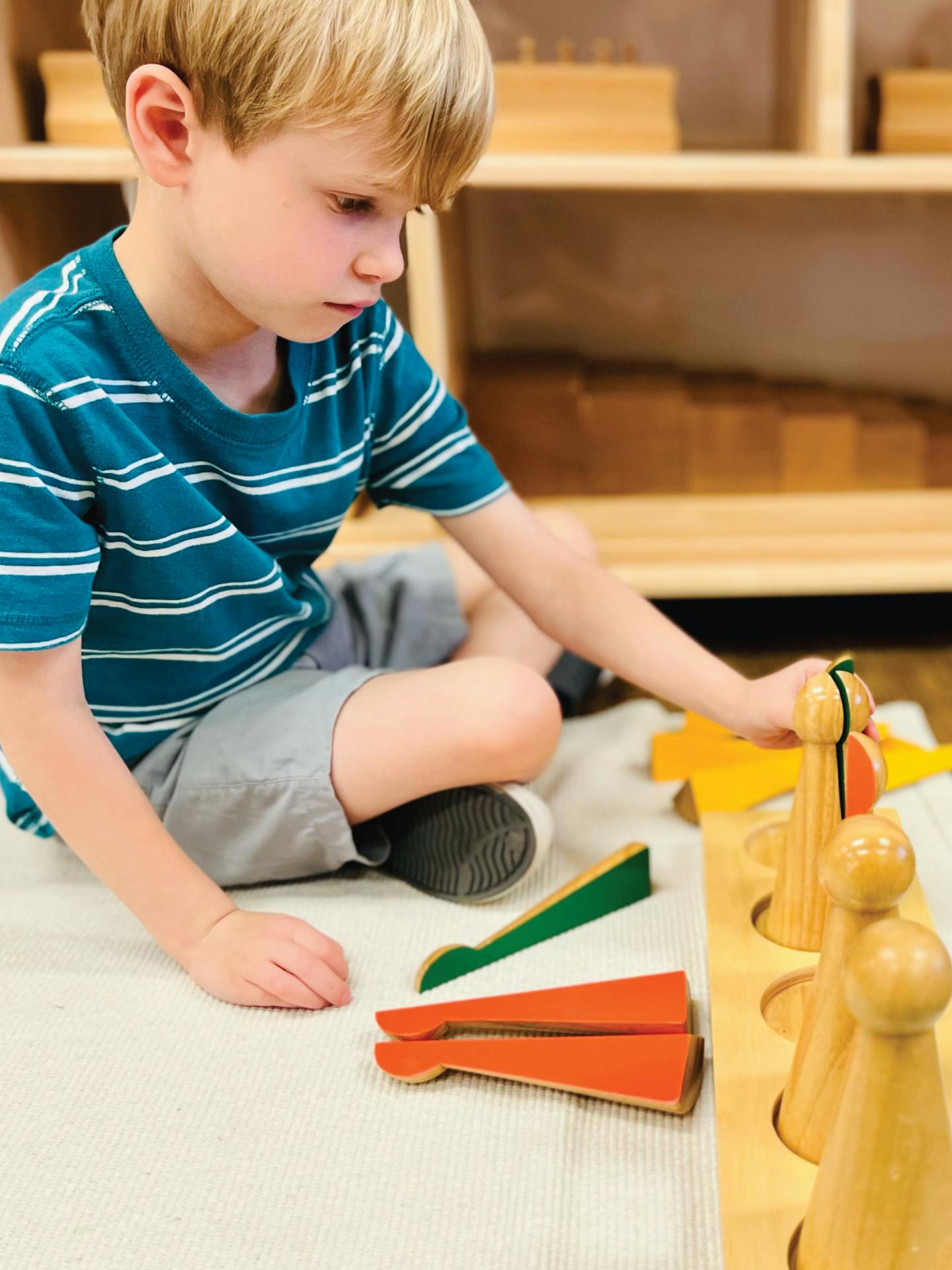 Child playing with wooden educational toys on the floor