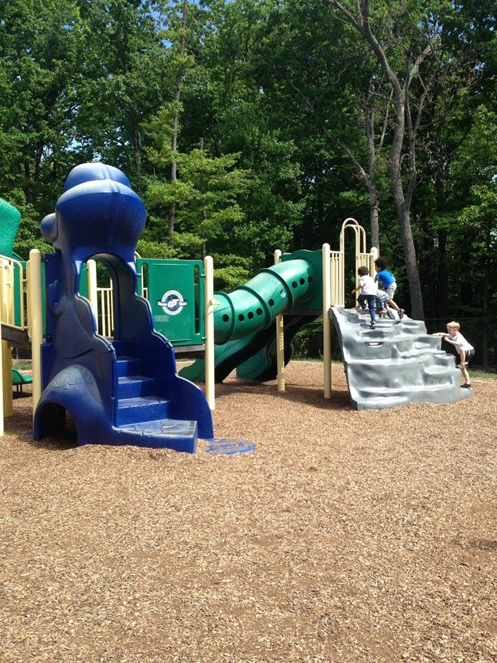Children playing on a playground structure with slides and climbing wall