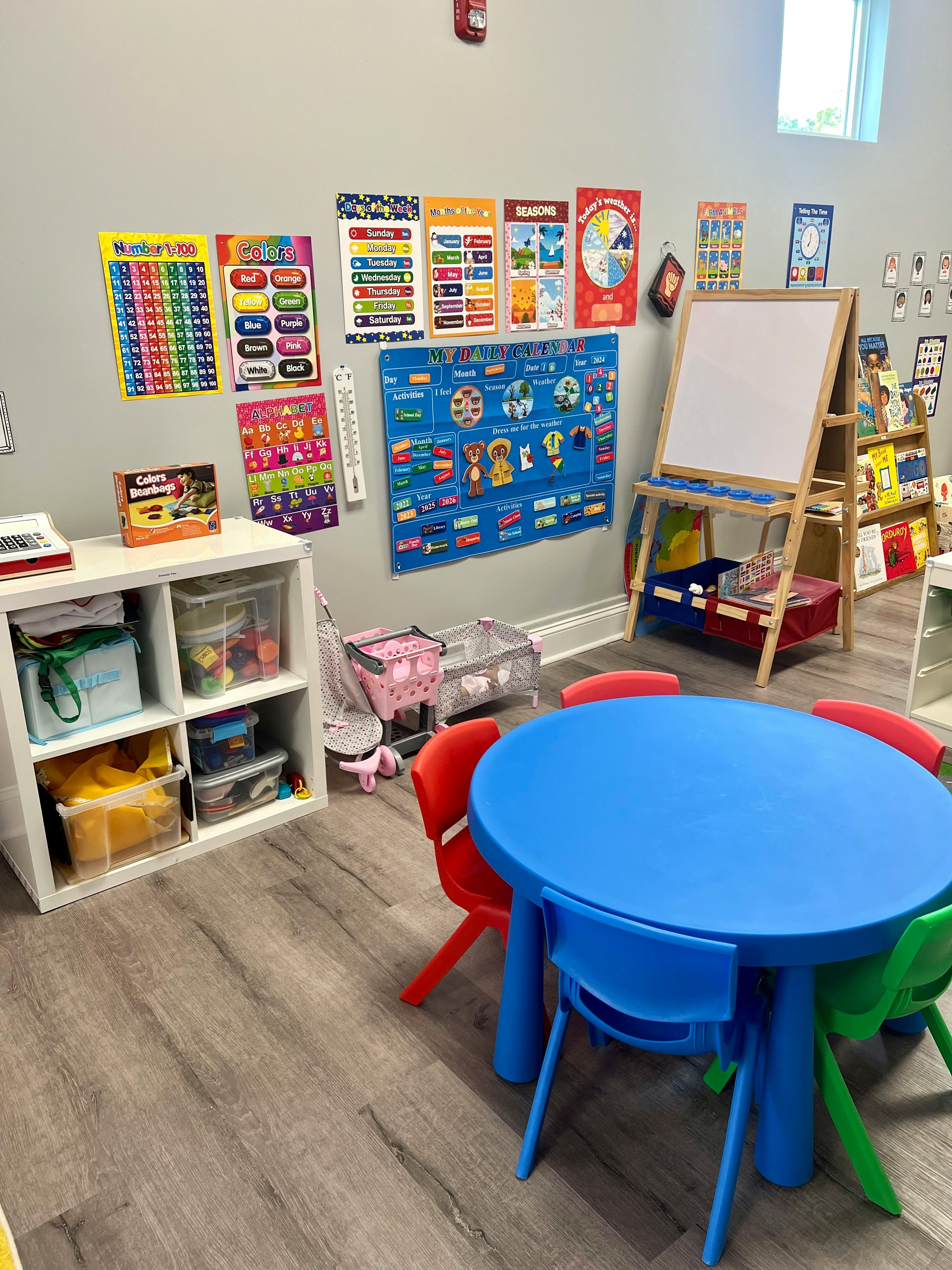 Classroom with a blue table and colorful chairs, shelves, and educational posters
