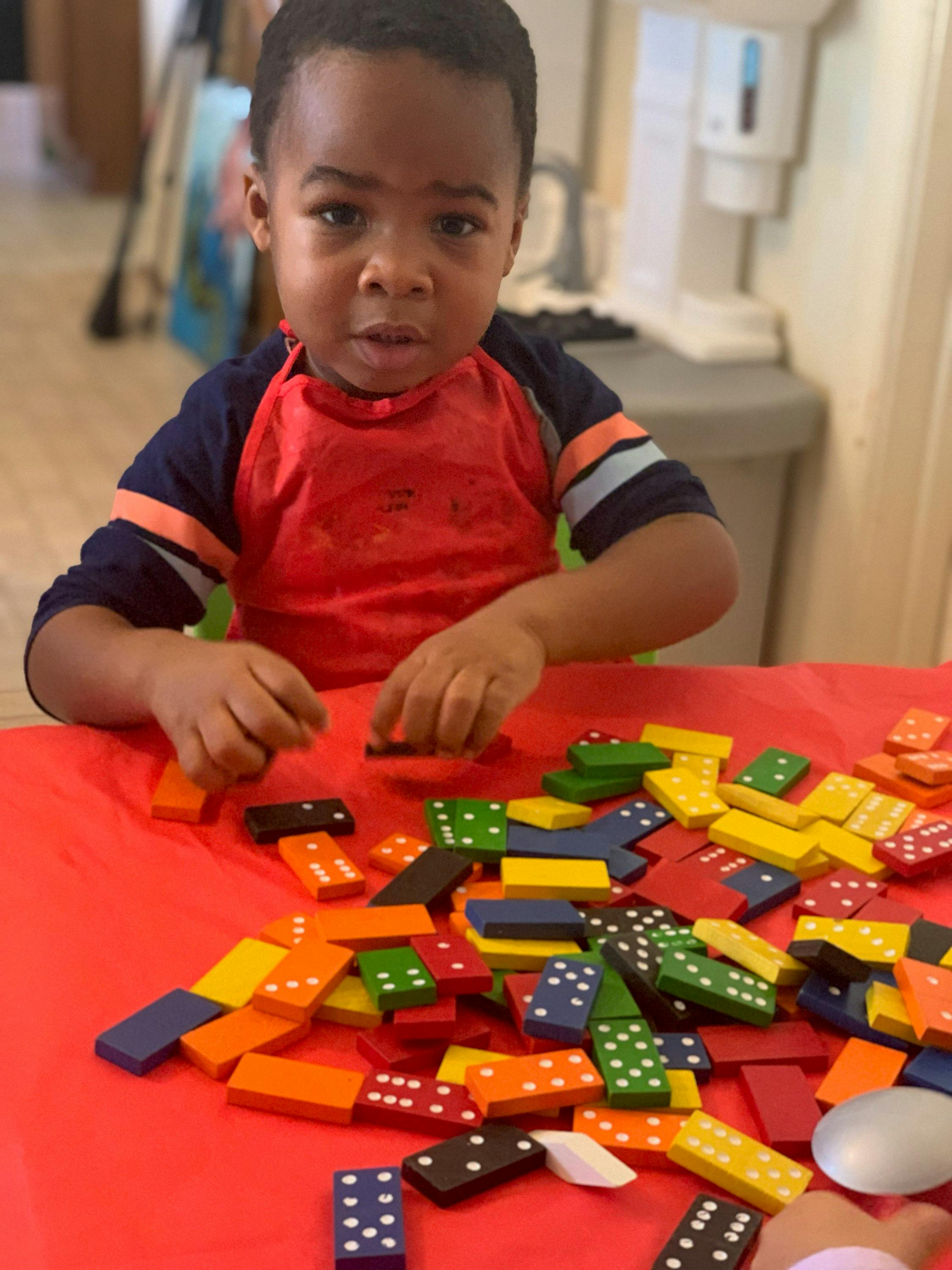 Child playing with colorful dominoes on a table