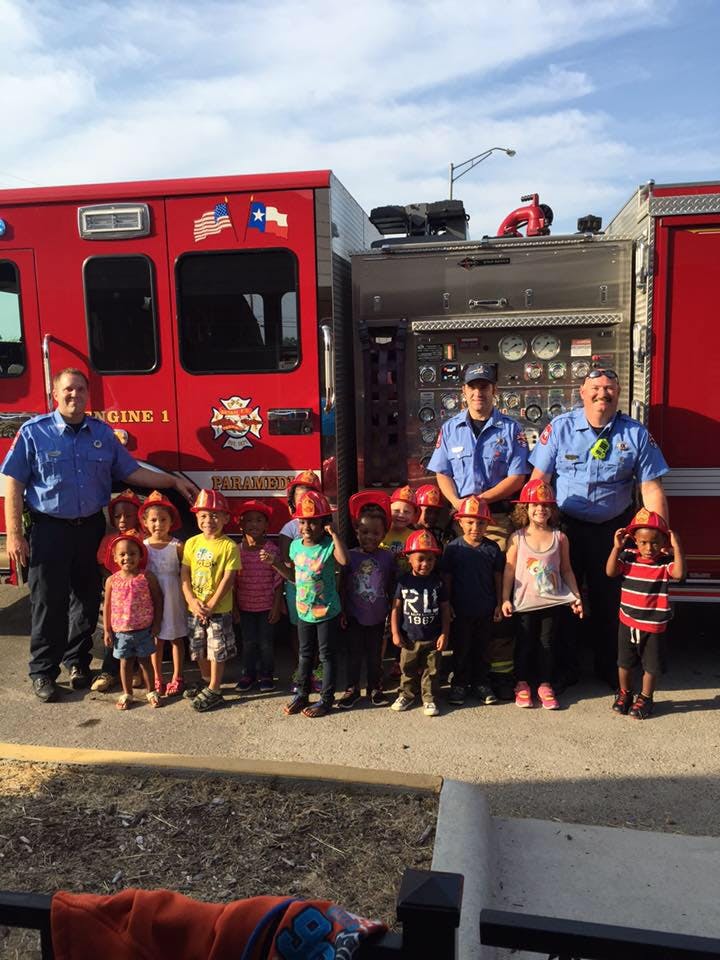 Firefighters and children in front of a fire truck