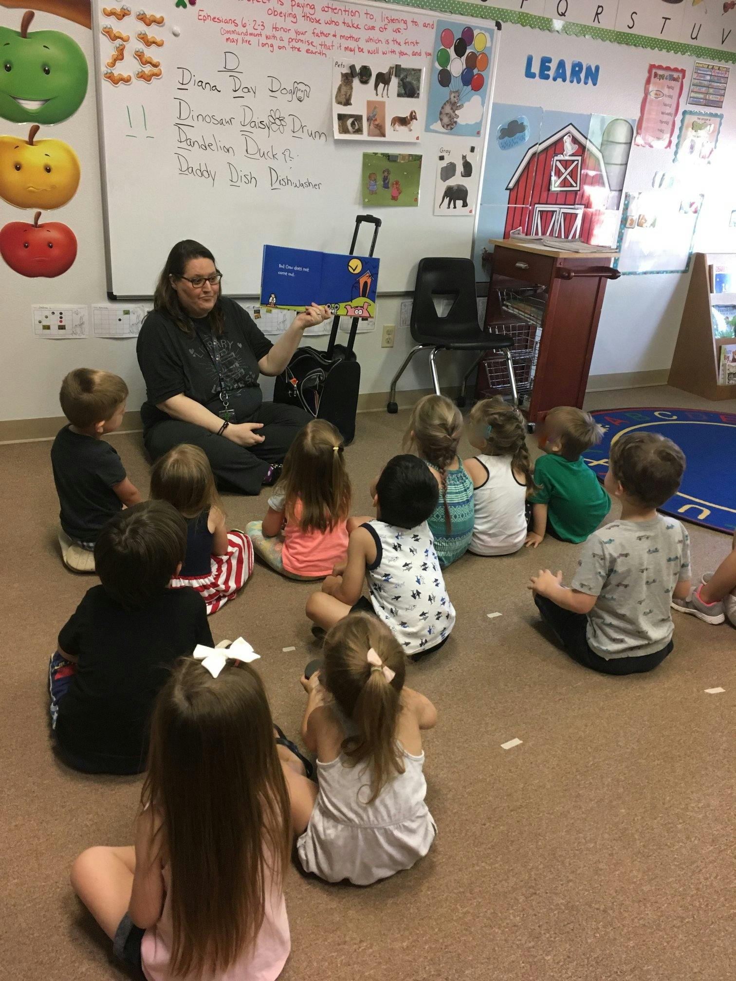 Person reading a book to a group of children in a classroom