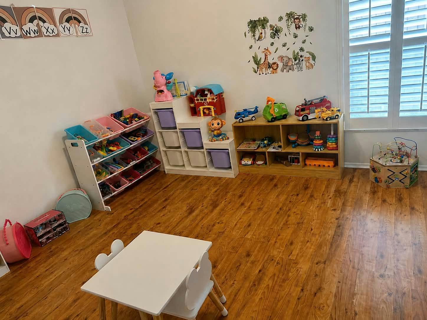 Playroom with shelves filled with toys and a small table with chairs