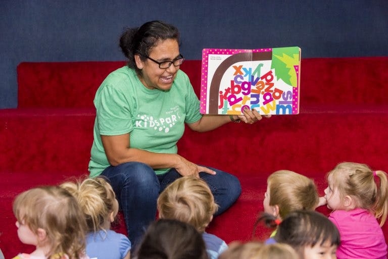 Person reading a book to a group of children