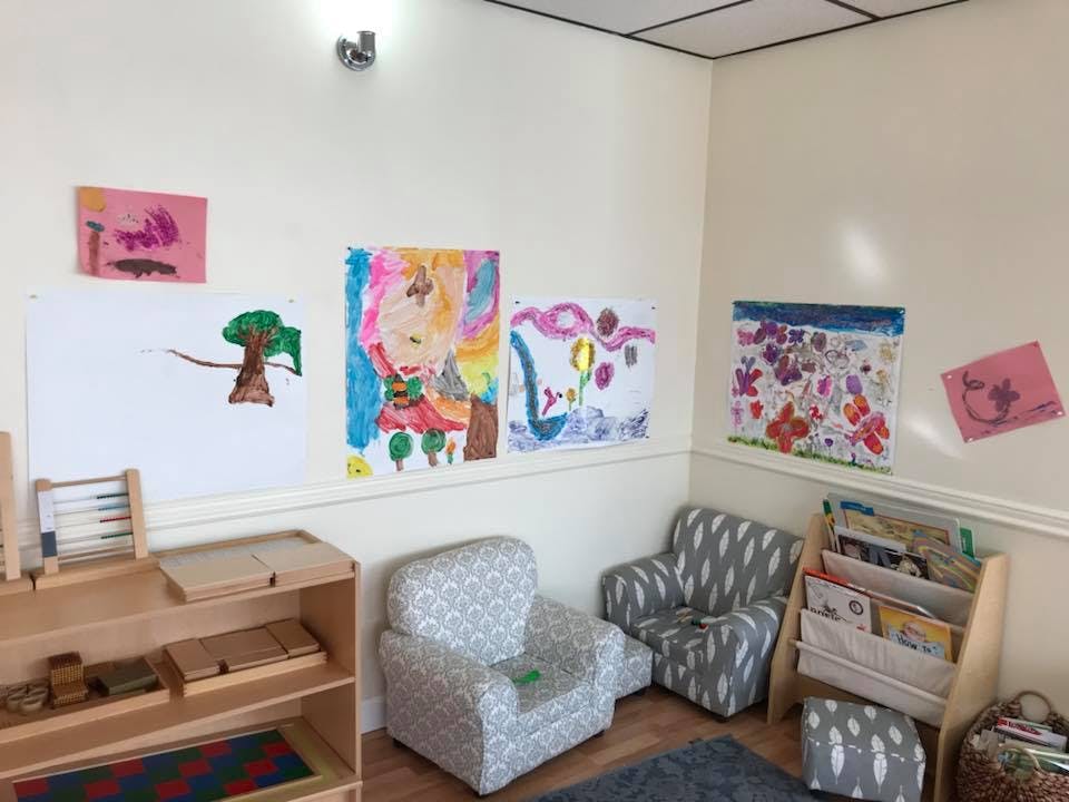 Children's artwork displayed on a wall above small chairs and shelves