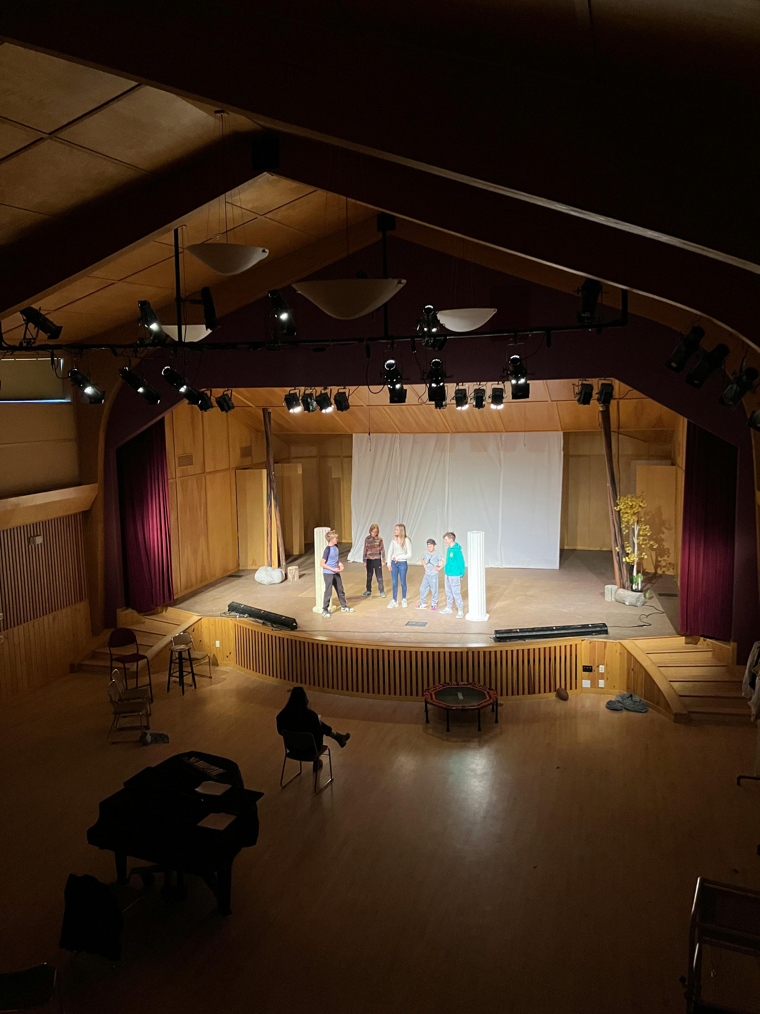 Five people standing on a stage with a person sitting in the foreground