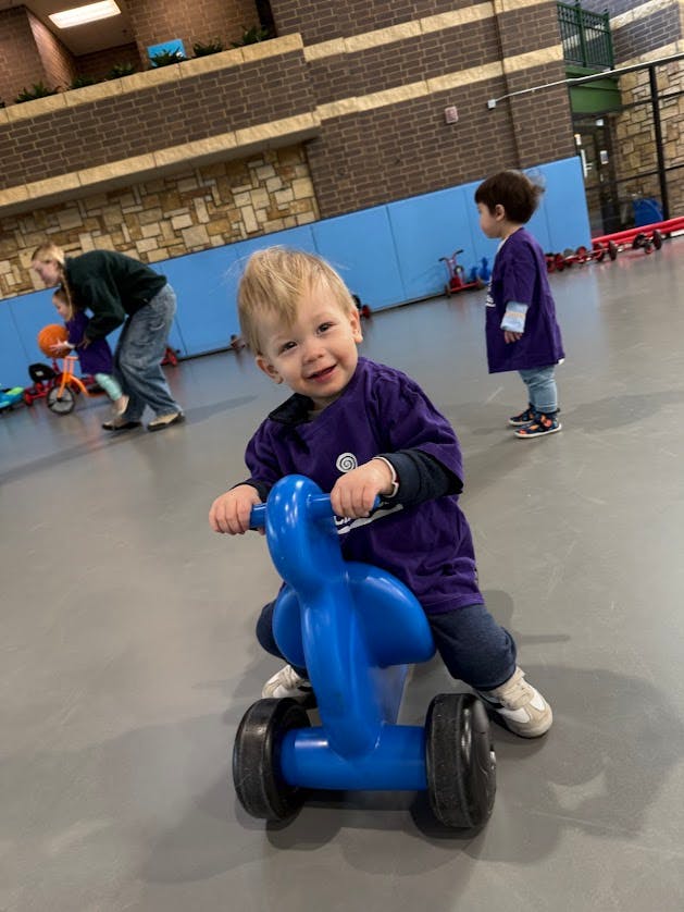 Child riding a blue toy bicycle indoors