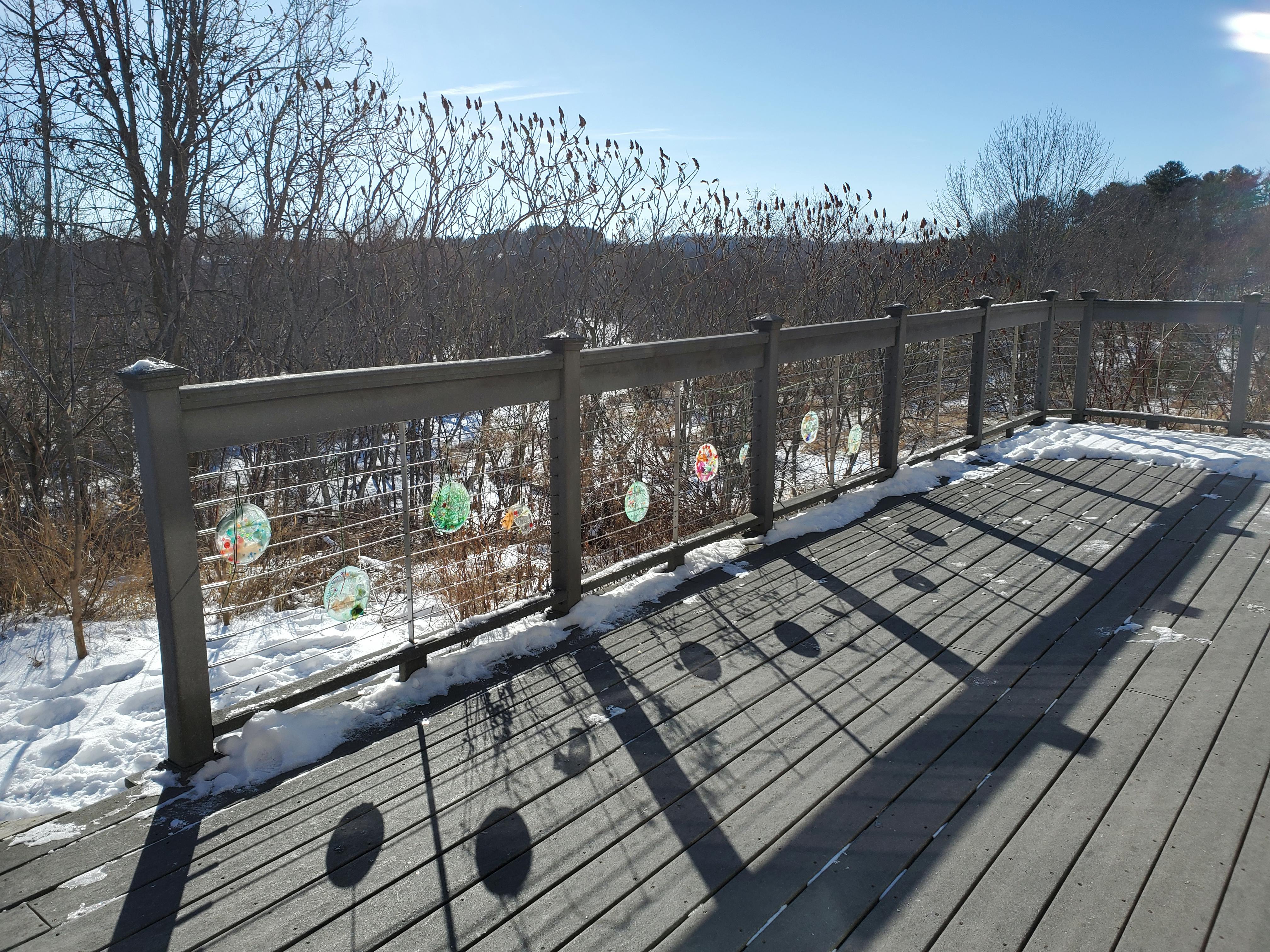 Deck railing with decorations and snow on the ground