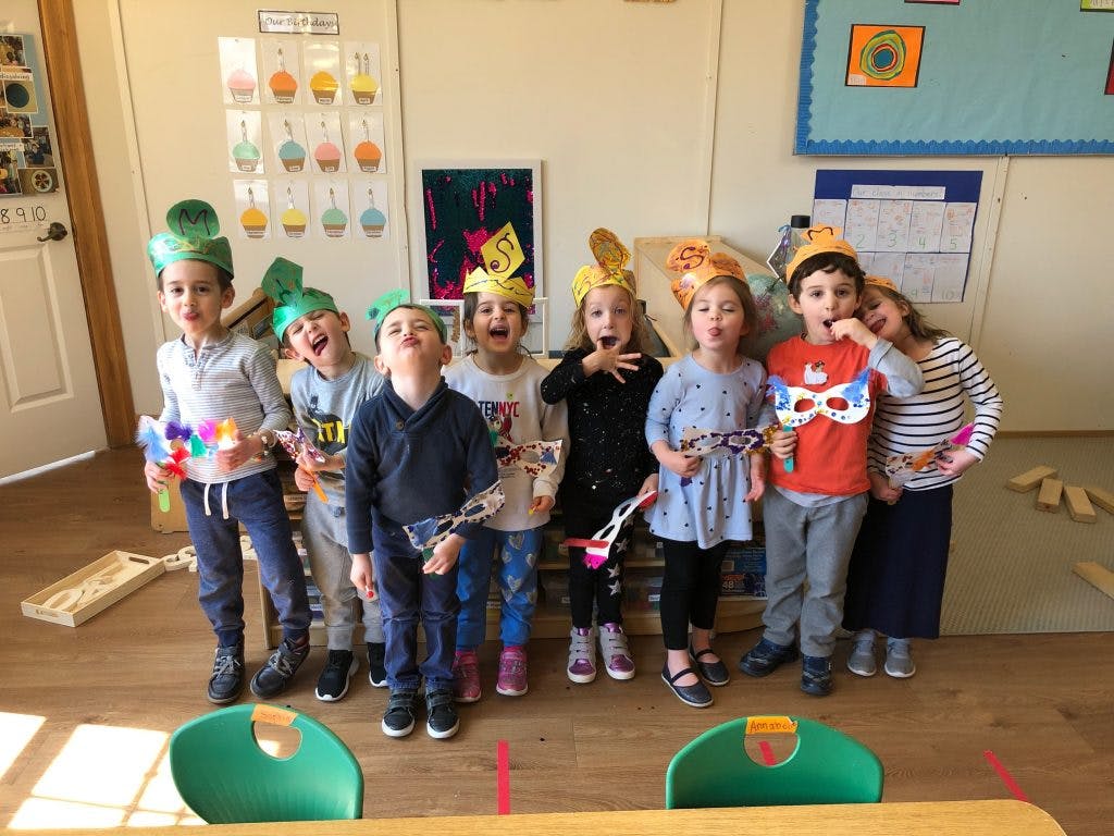 Group of children wearing hats and holding props in a classroom